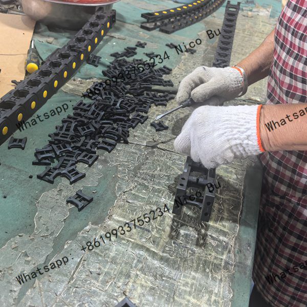 factory-worker-assembling-plastic-cable-drag-chain-components-on-production-workbench